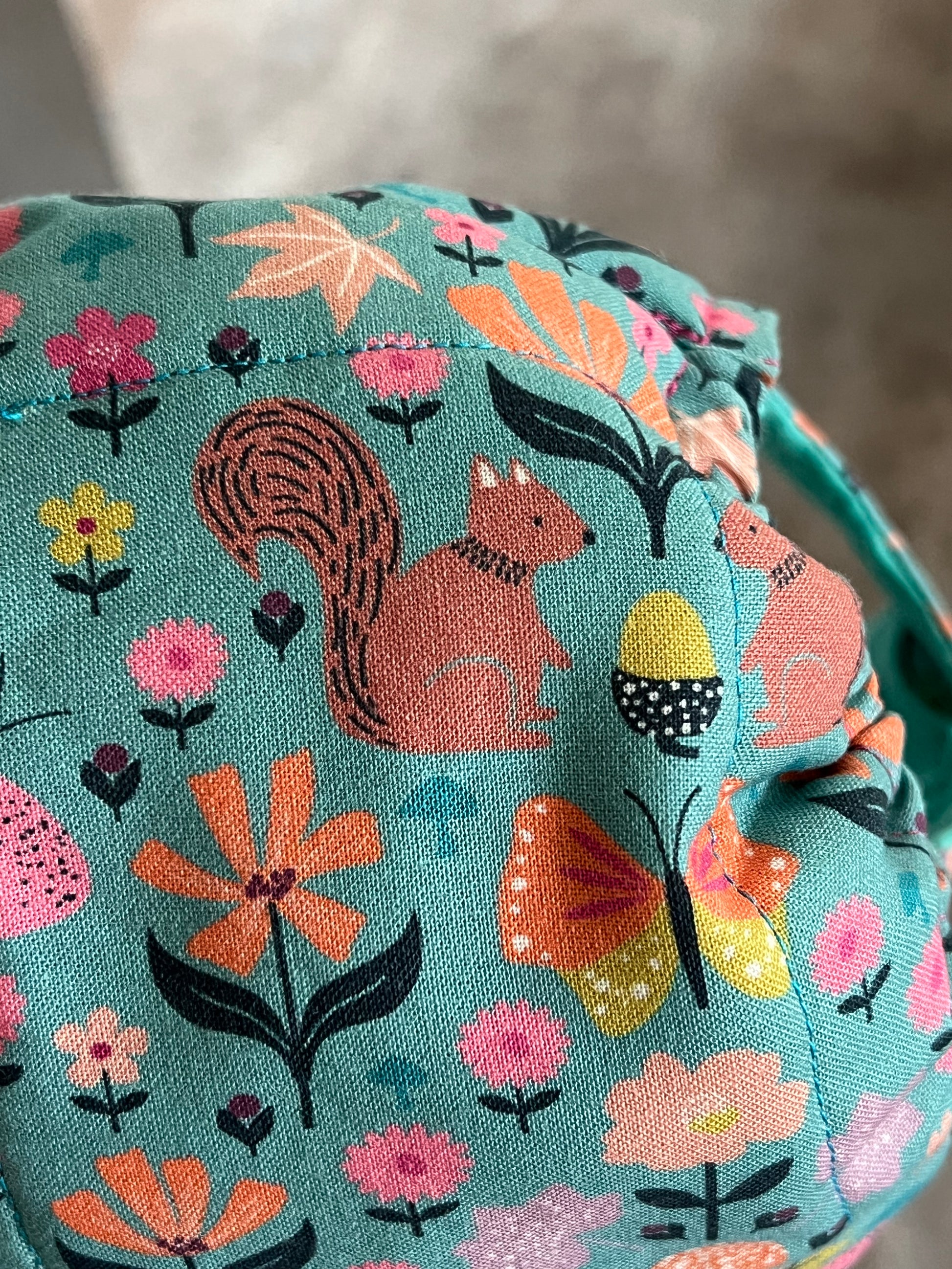 Fabric with a squirrel and floral pattern on a teal background